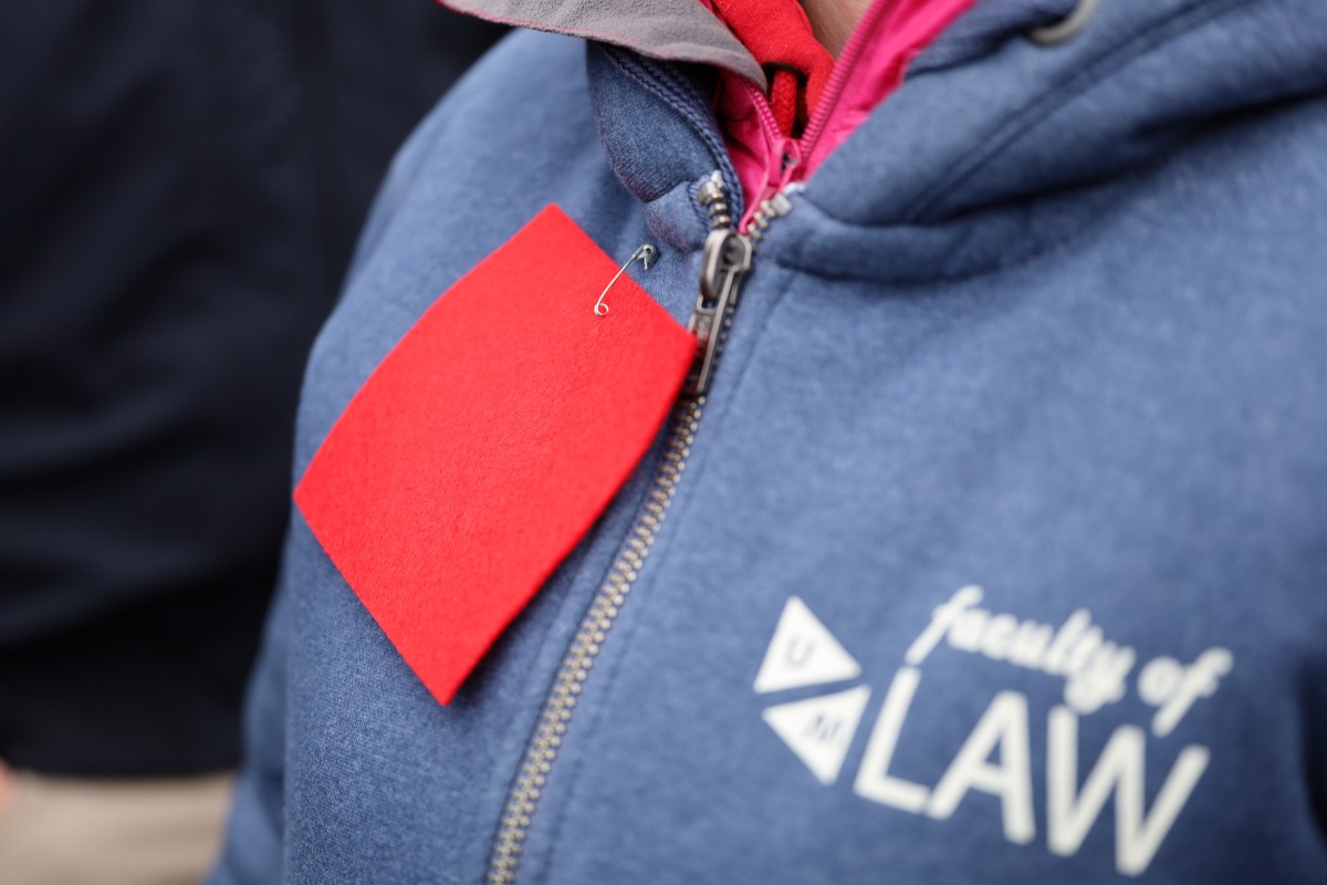 A red square (the symbol of the protests) pinned to a university sweater.